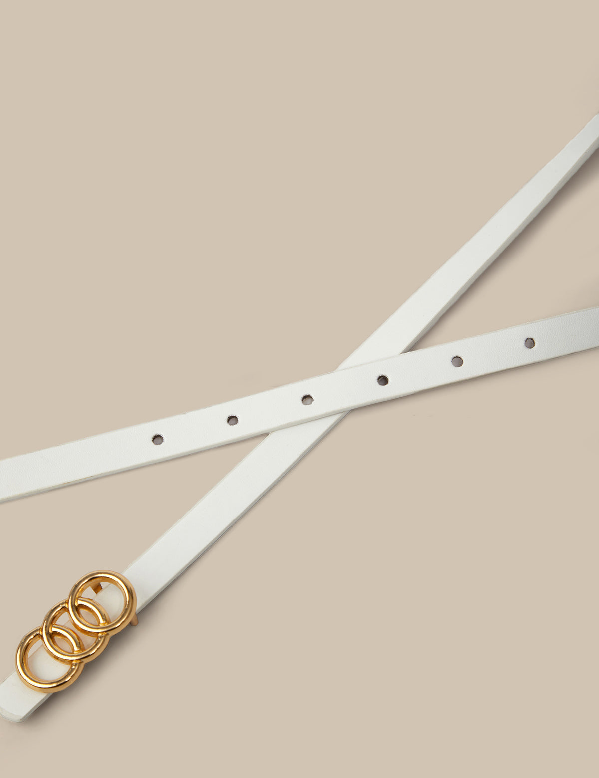 White belt with gold buckle on a beige background