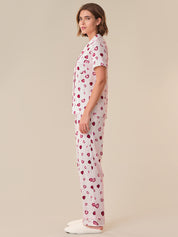 Woman wearing a white pajama set with red heart patterns on a beige background