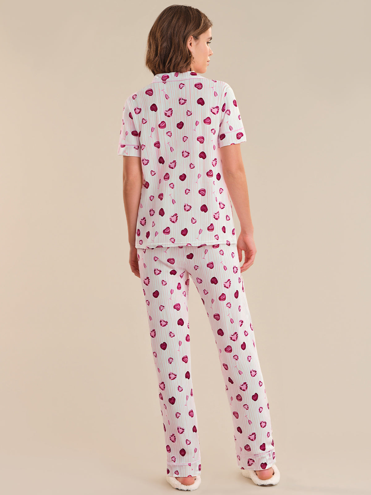 Person wearing a heart-patterned pajama set on a beige background