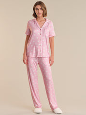 Woman wearing a pink polka dot pajama set on a beige background
