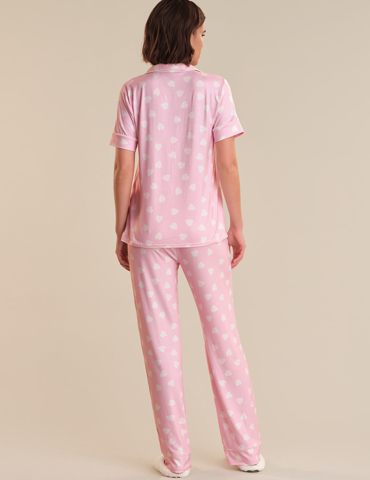 Person wearing pink polka dot pajamas on a beige background