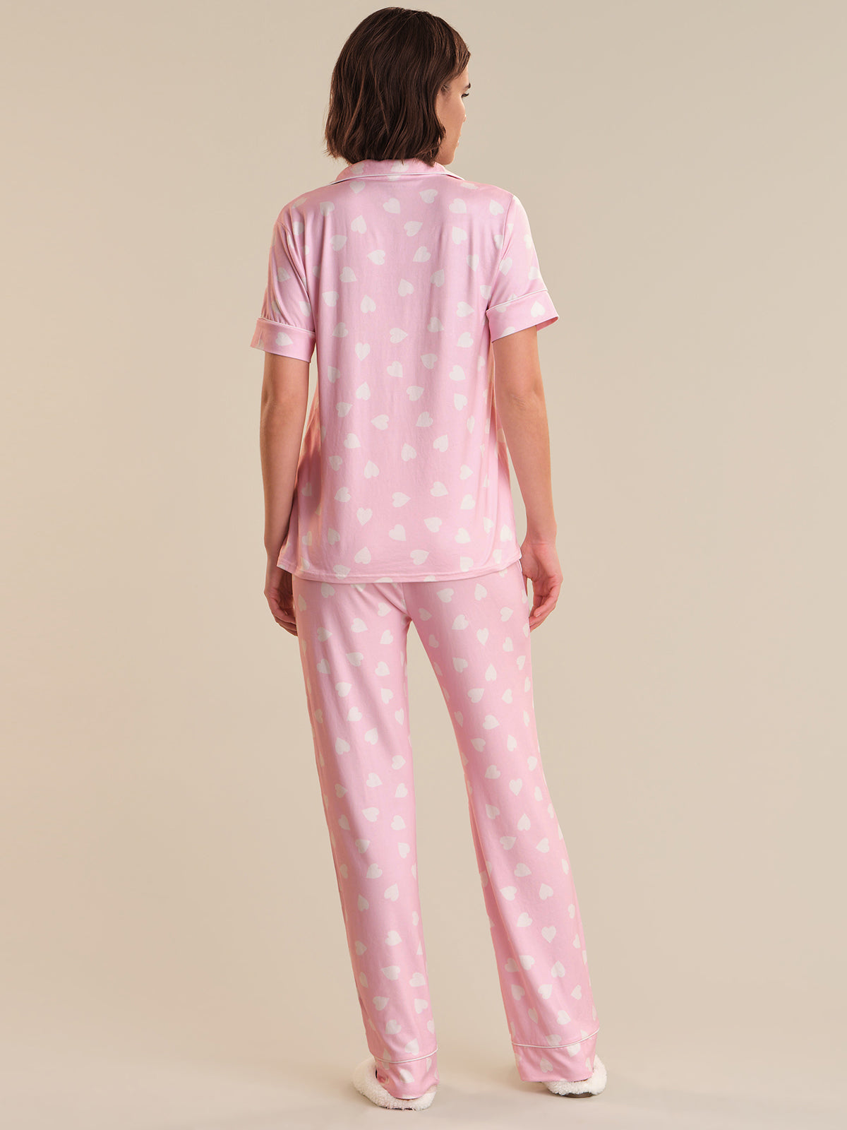 Person wearing pink polka dot pajamas on a beige background