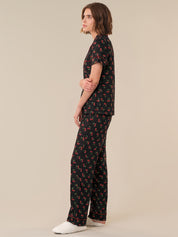 Woman wearing a black floral jumpsuit on a beige background