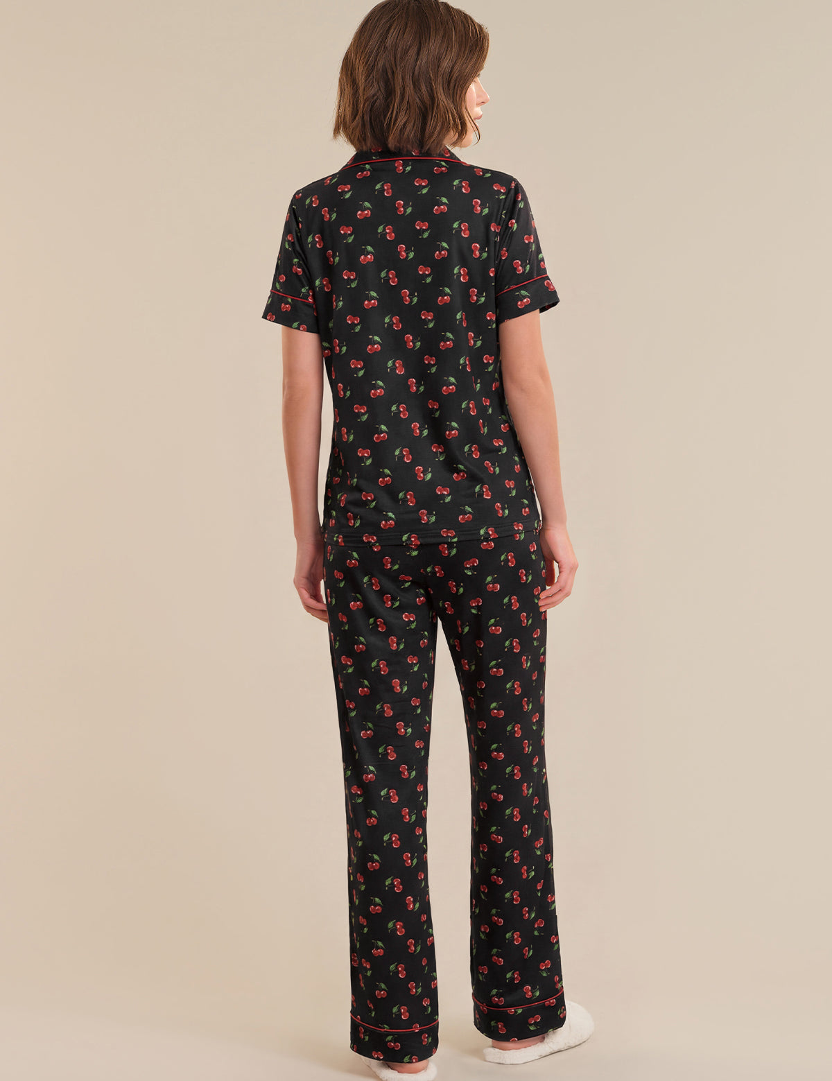 Person wearing a black patterned outfit on a beige background