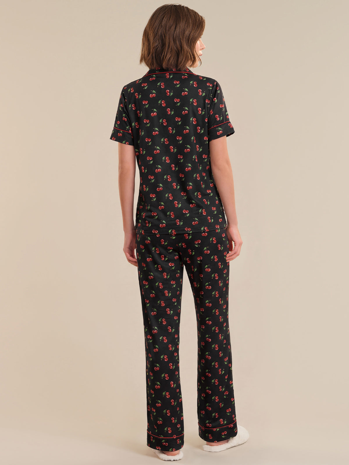 Person wearing a black patterned outfit on a beige background