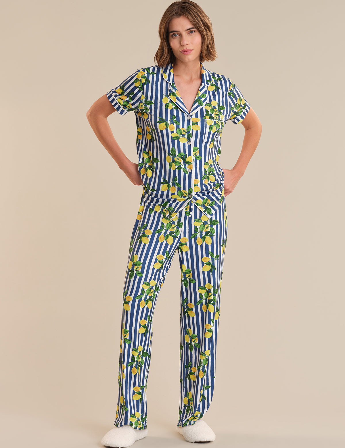 Woman wearing a blue and white striped jumpsuit with lemon pattern on a beige background