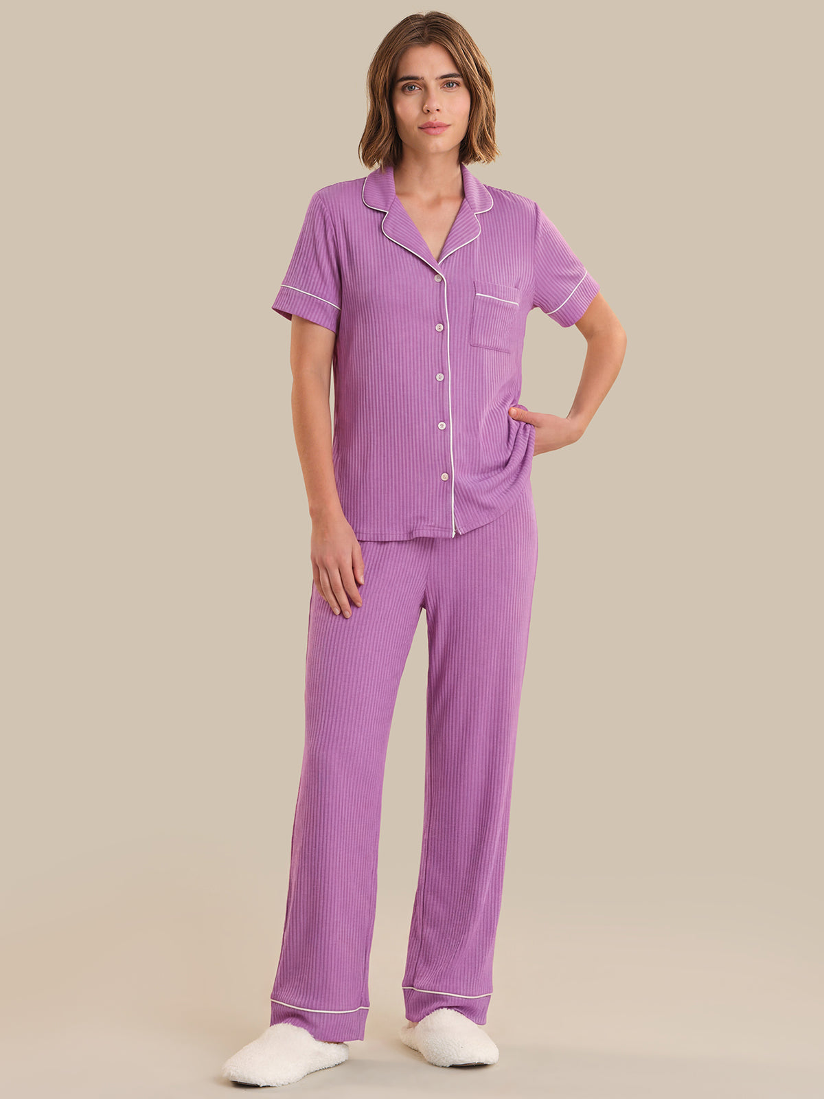 Woman wearing a purple pajama set on a beige background