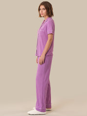 Woman wearing a purple pajama set on a beige background