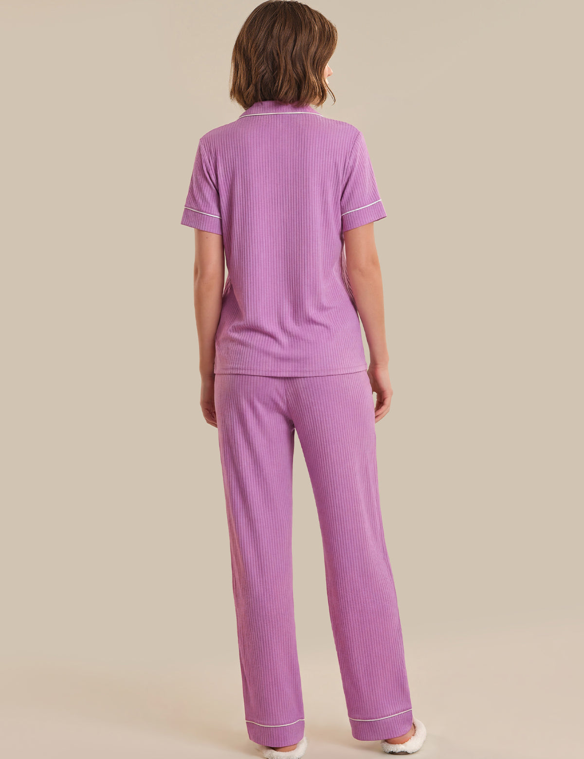 Person wearing a purple pajama set on a beige background