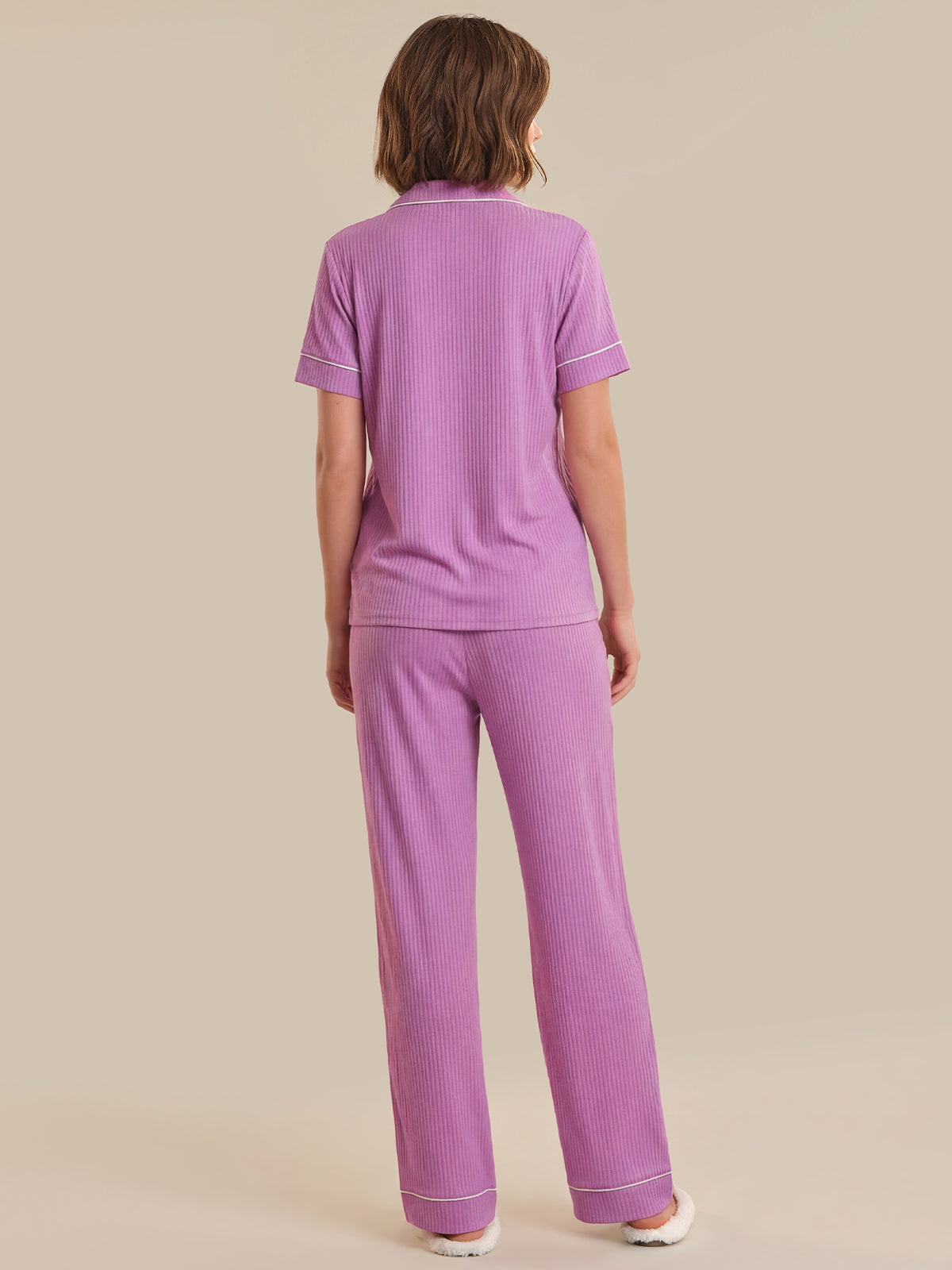 Person wearing a purple pajama set on a beige background