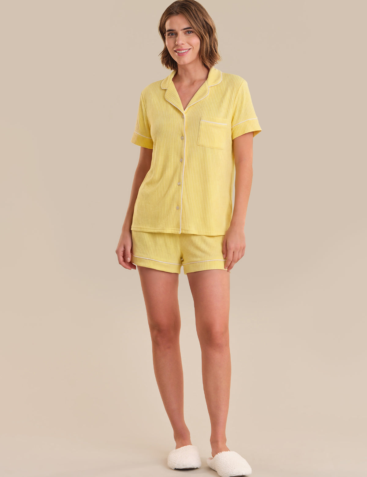 Woman wearing a yellow pajama set on a beige background