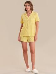 Woman wearing a yellow pajama set on a beige background