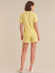 Woman wearing a yellow pajama set on a beige background
