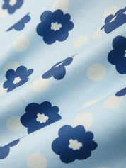Close-up of fabric with blue floral and polka dot pattern on light blue background