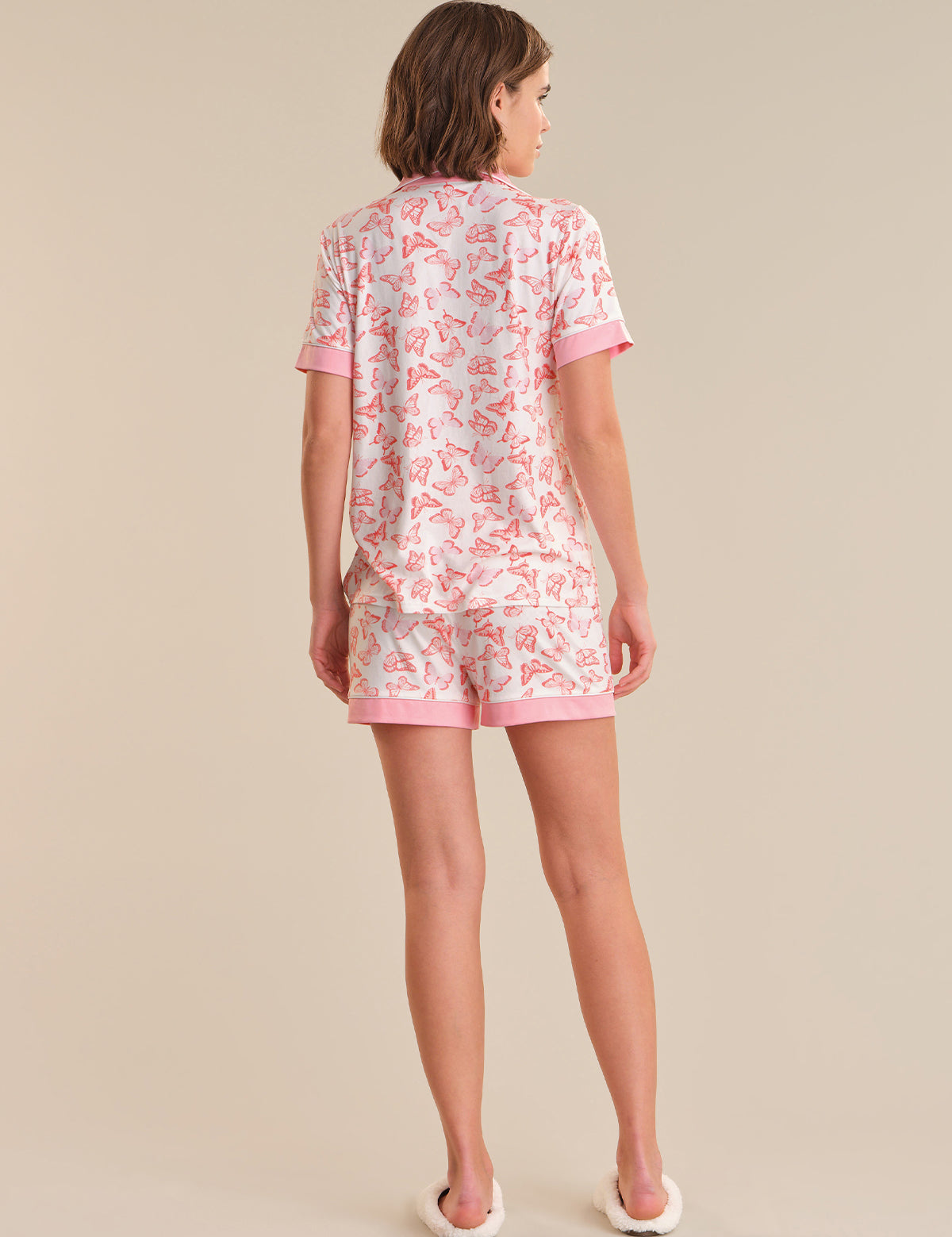 Woman wearing a pink butterfly pajama set on a beige background