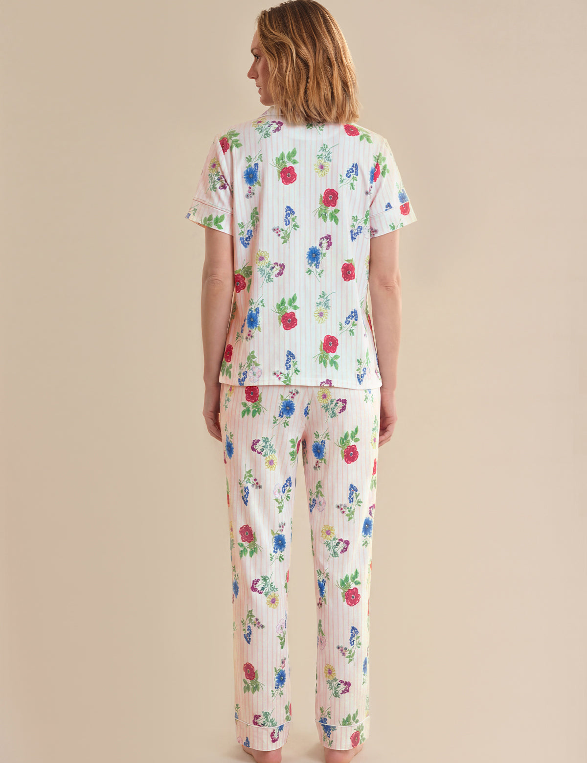 Woman wearing a floral pajama set on a beige background