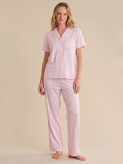 Woman wearing a pink striped pajama set on a beige background