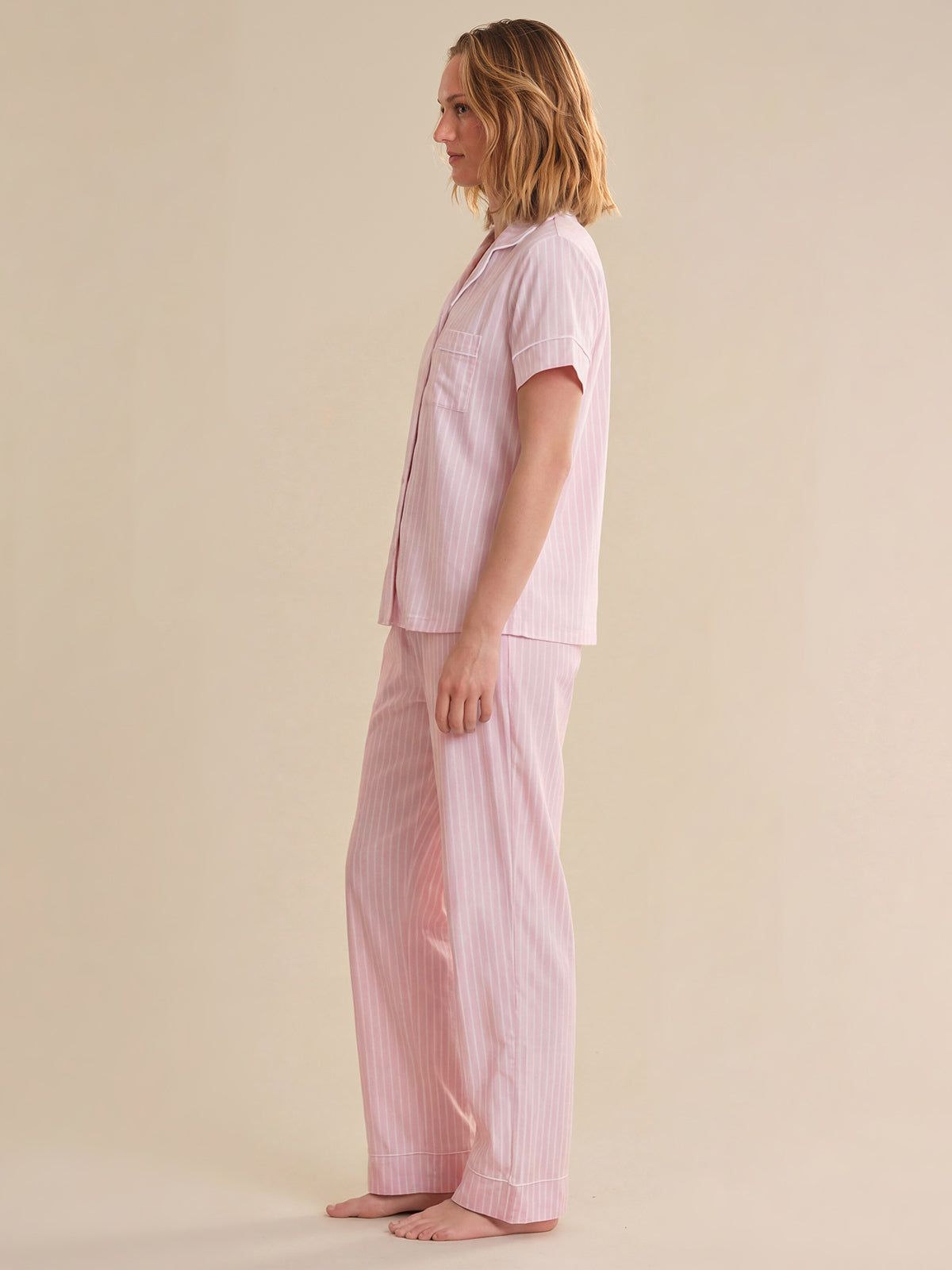 Person wearing pink striped pajamas on a beige background