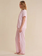 Person wearing pink striped pajamas on a beige background
