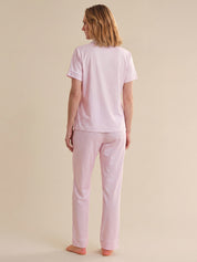 Woman wearing a pink striped pajama set against a beige background