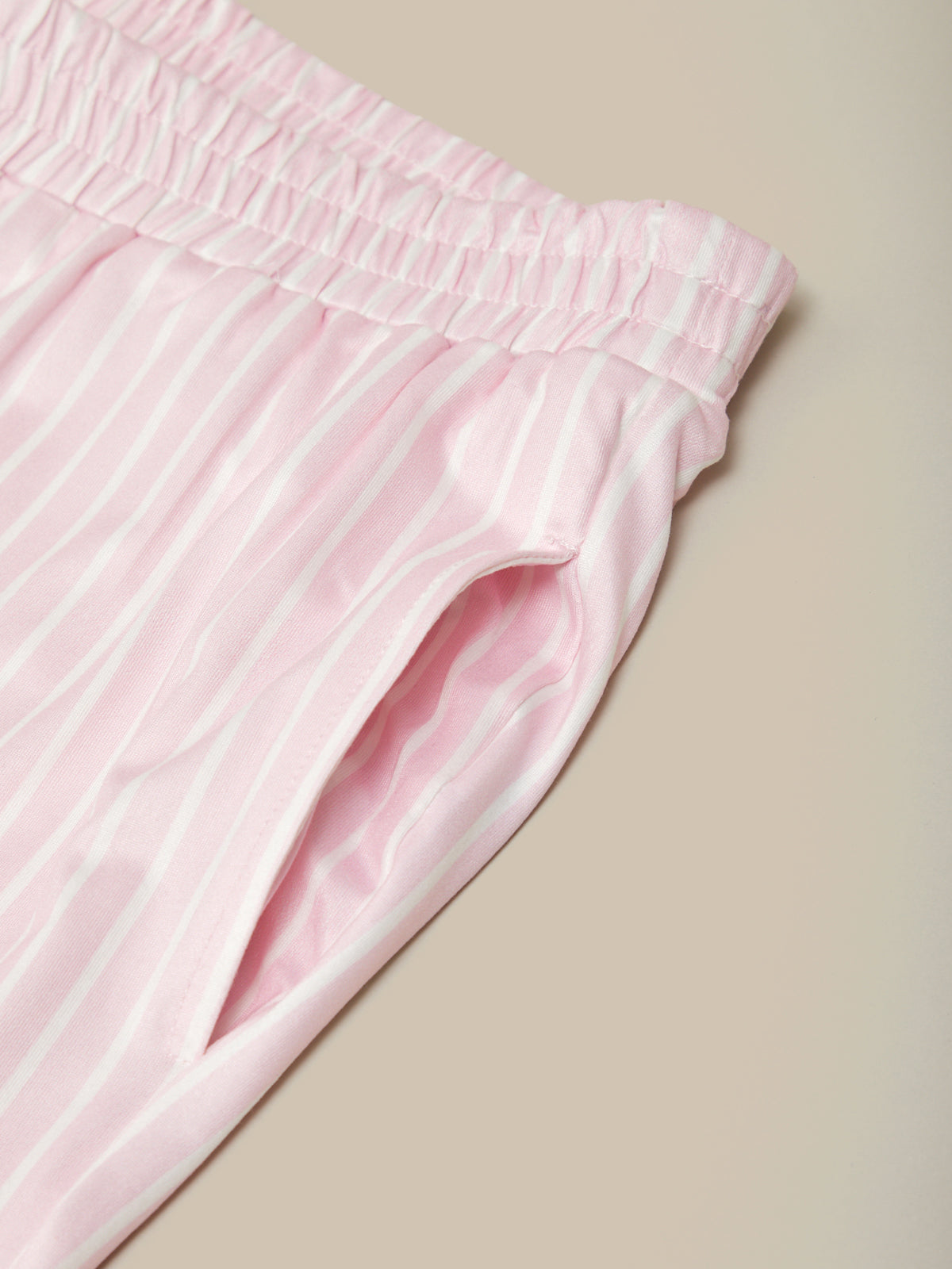 Close-up of pink pants with white stripes on a beige background