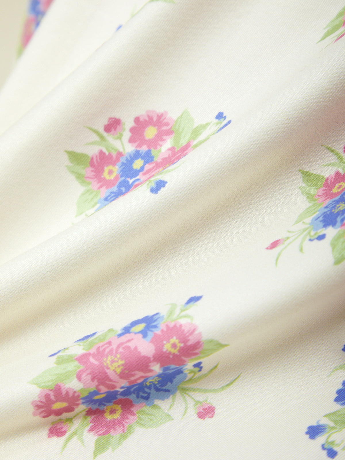 Floral pattern on fabric with pink, blue, and green flowers on a beige background