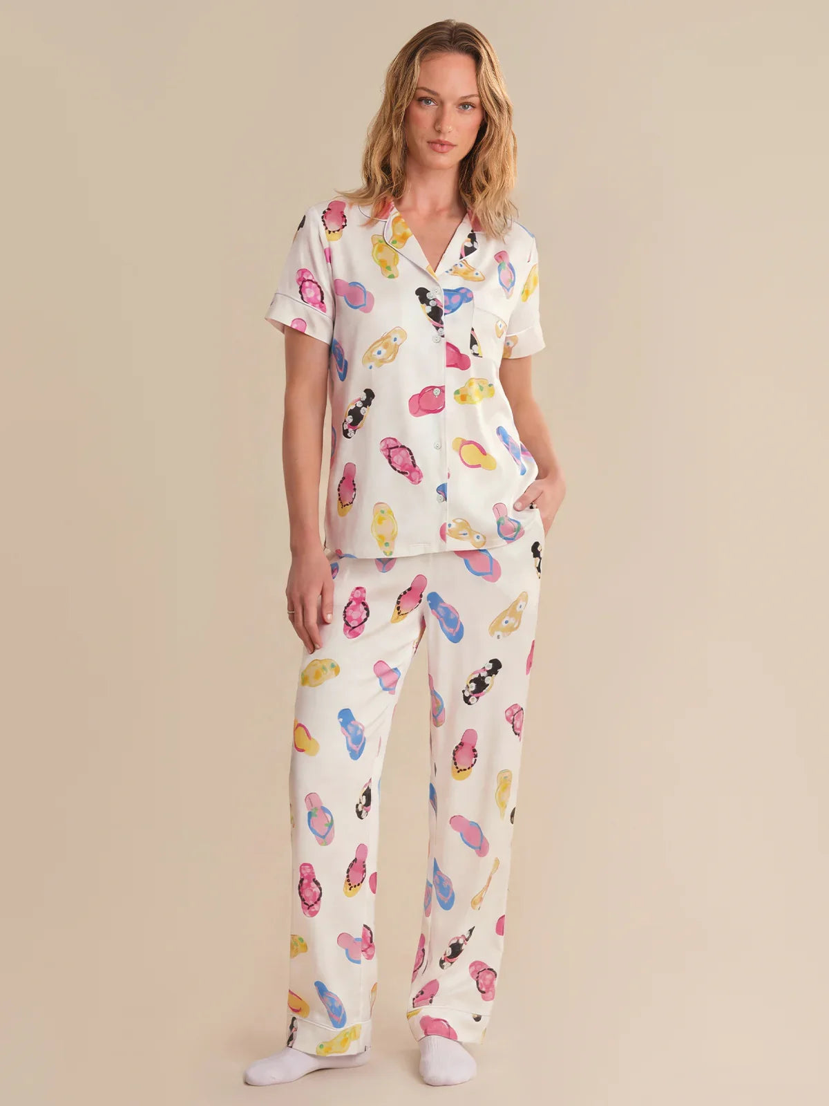 Woman wearing a colorful pajama set with cartoon characters on a beige background
