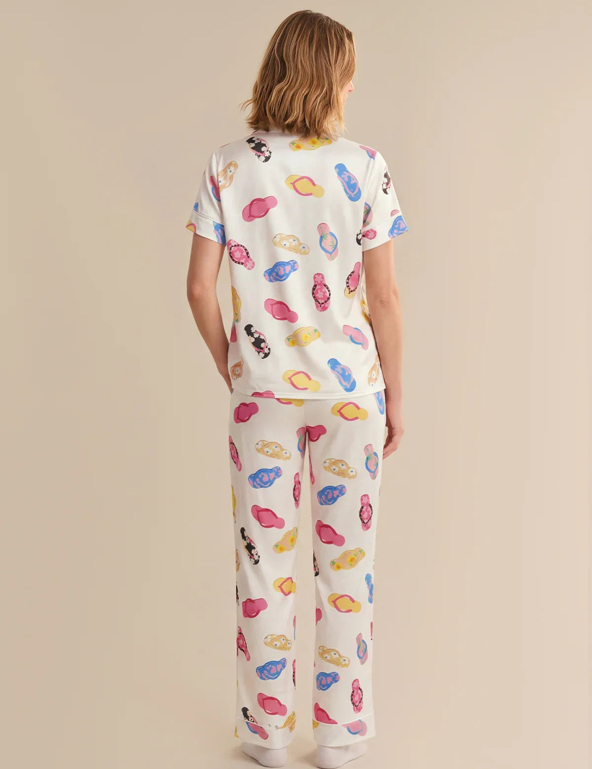 Person wearing a colorful pajama set with cartoon designs on a beige background