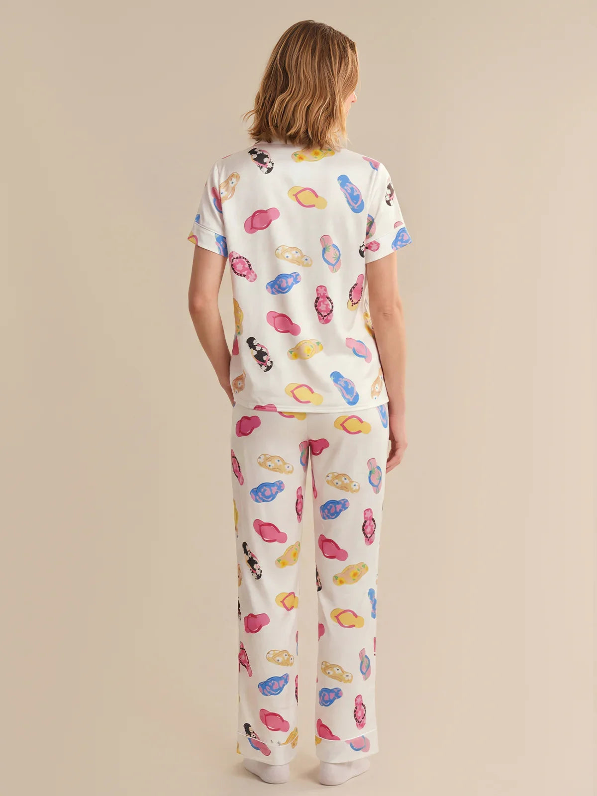 Person wearing a colorful pajama set with cartoon designs on a beige background