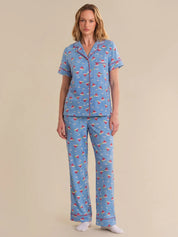 Woman wearing a blue pajama set with a pattern on a beige background