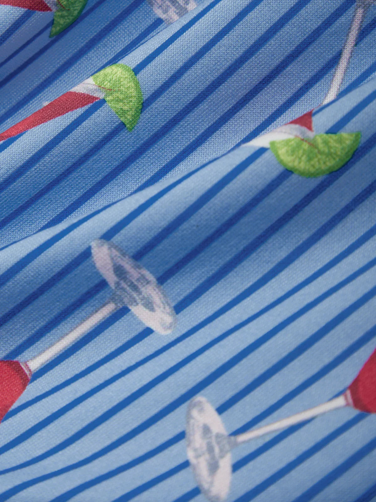 Pattern of cocktail glasses with red liquid and green limes on a blue striped background