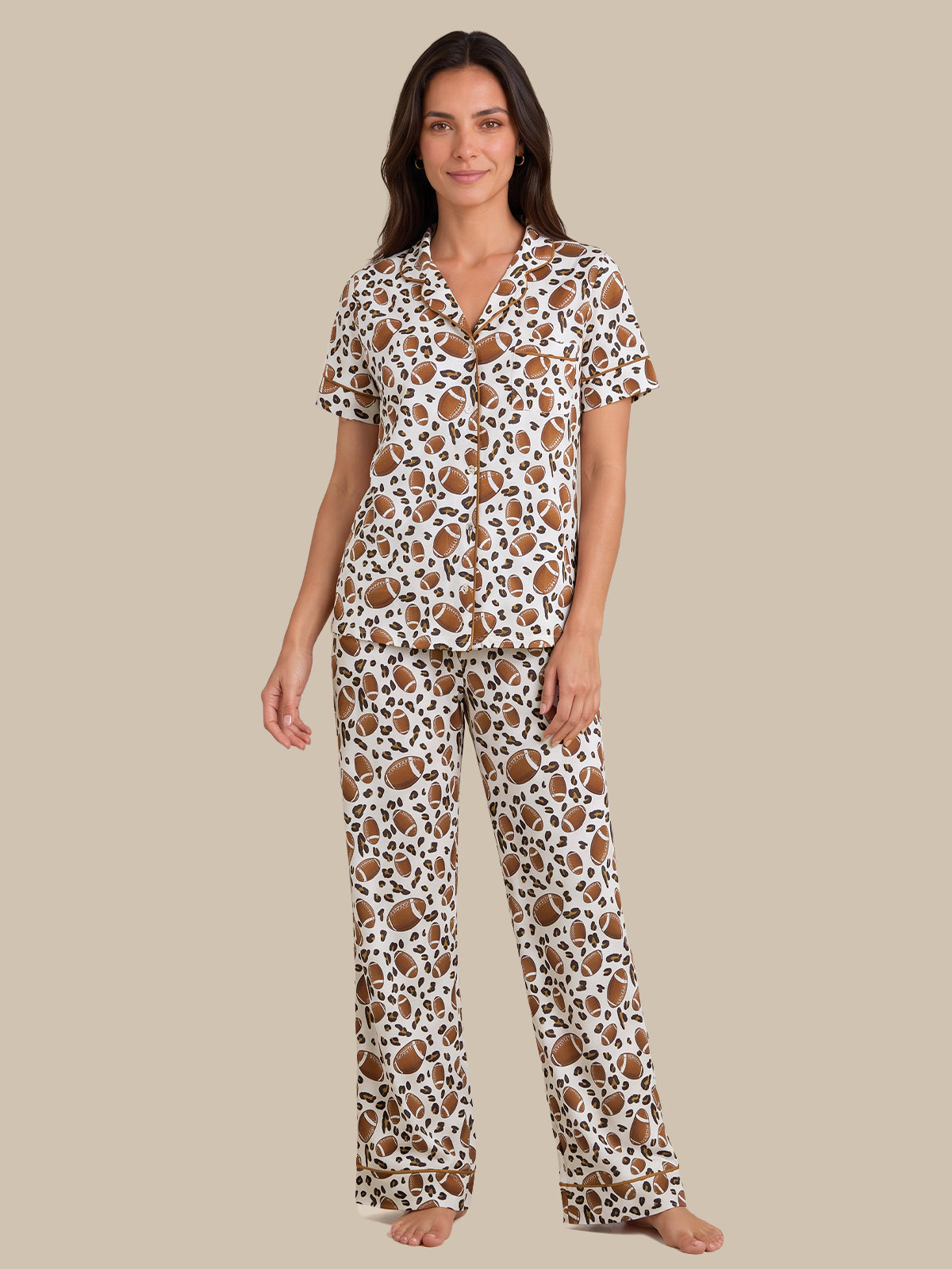 A woman modeling a matching short-sleeve button-front pajama top and wide-leg pajama pants set in a brown and black leopard print on a white background, set against a solid beige studio backdrop.