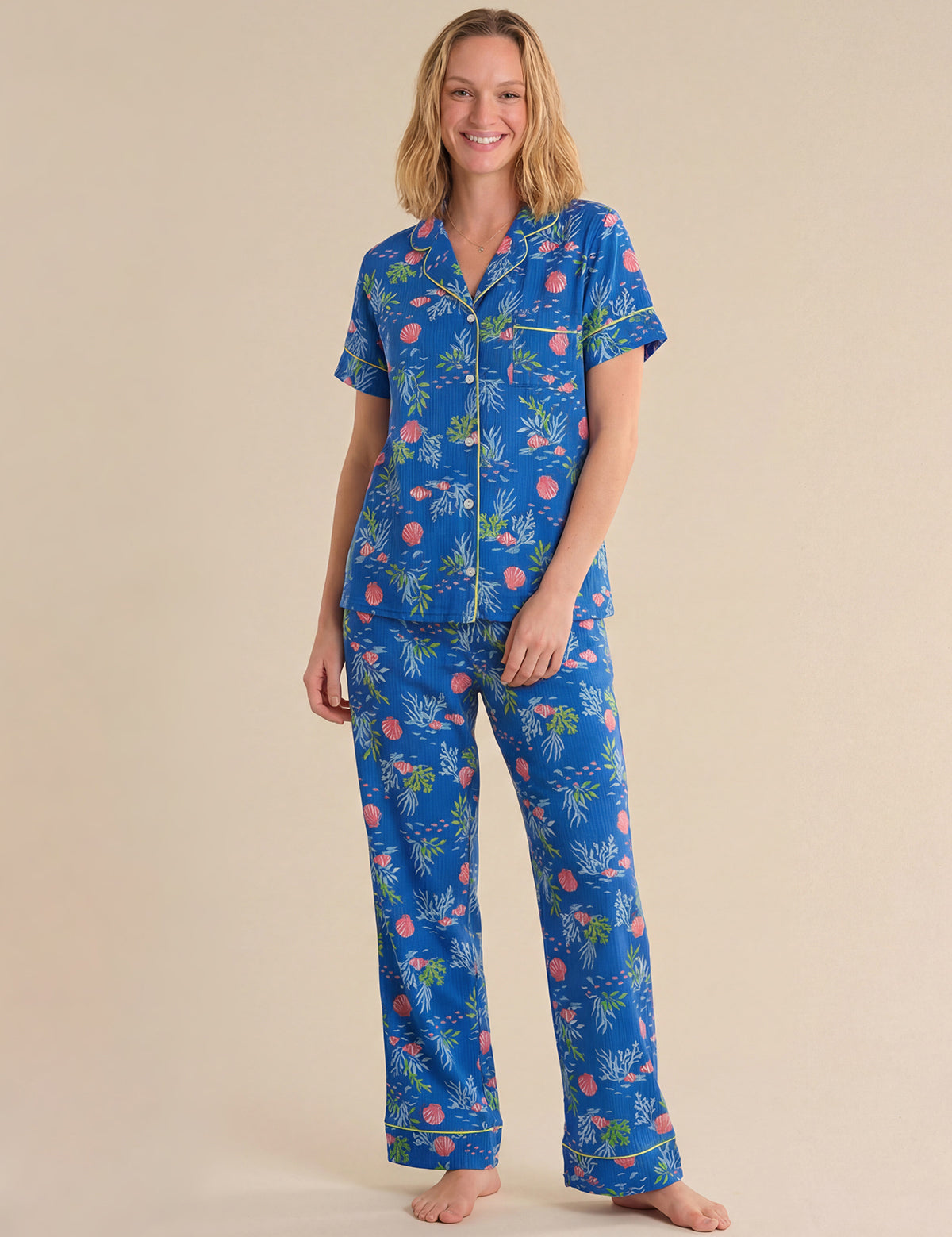 Woman wearing a blue tropical sea pajama set on a beige background