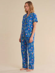 Woman wearing a blue tropical sea pajama set on a beige background