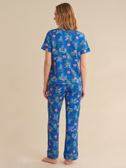 Person wearing a blue tropical sea pajama set on a beige background