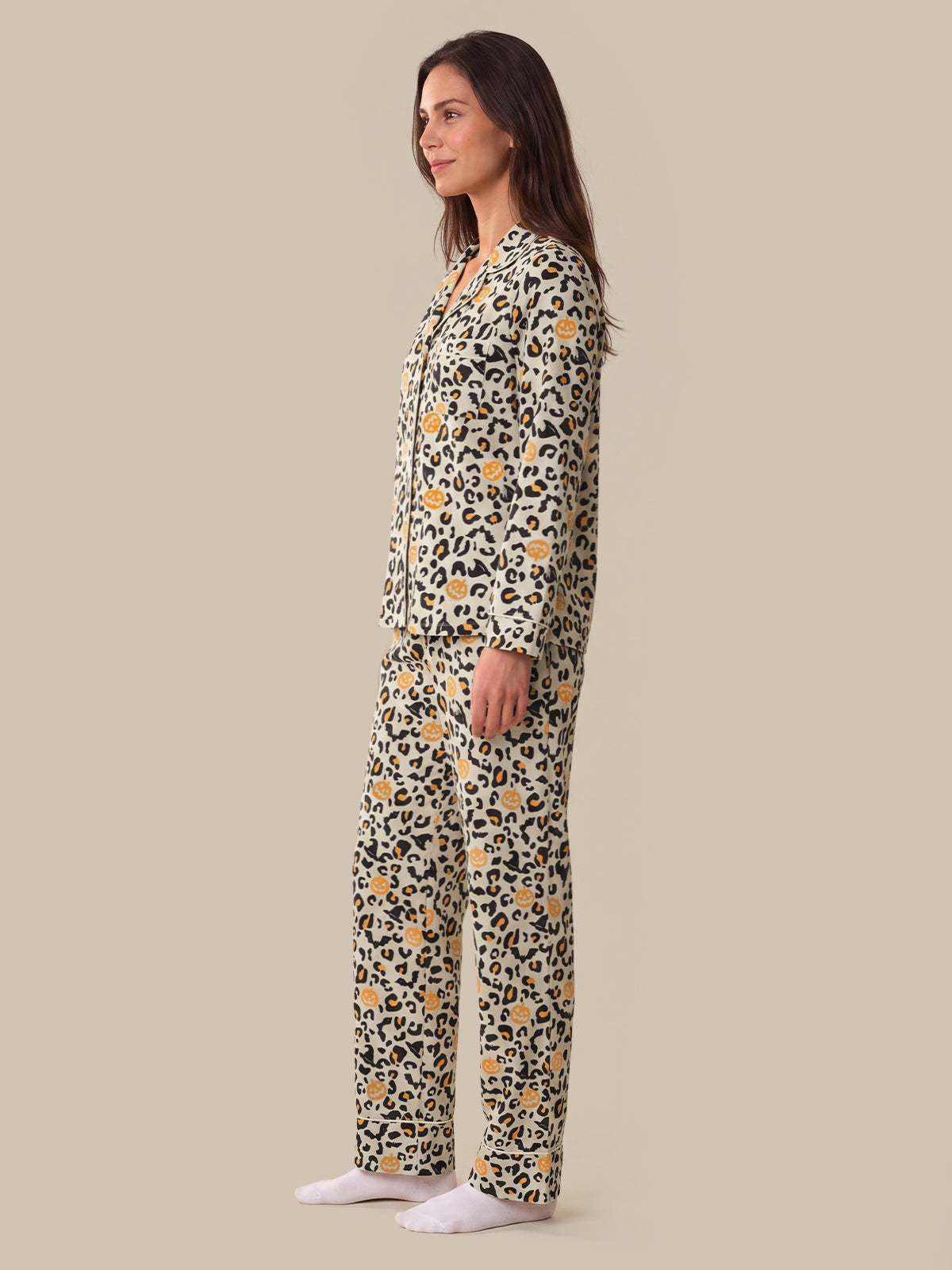 A woman modeling a matching two-piece pajama set with a leopard print pattern and small yellow floral accents, shown in profile against a solid beige background.