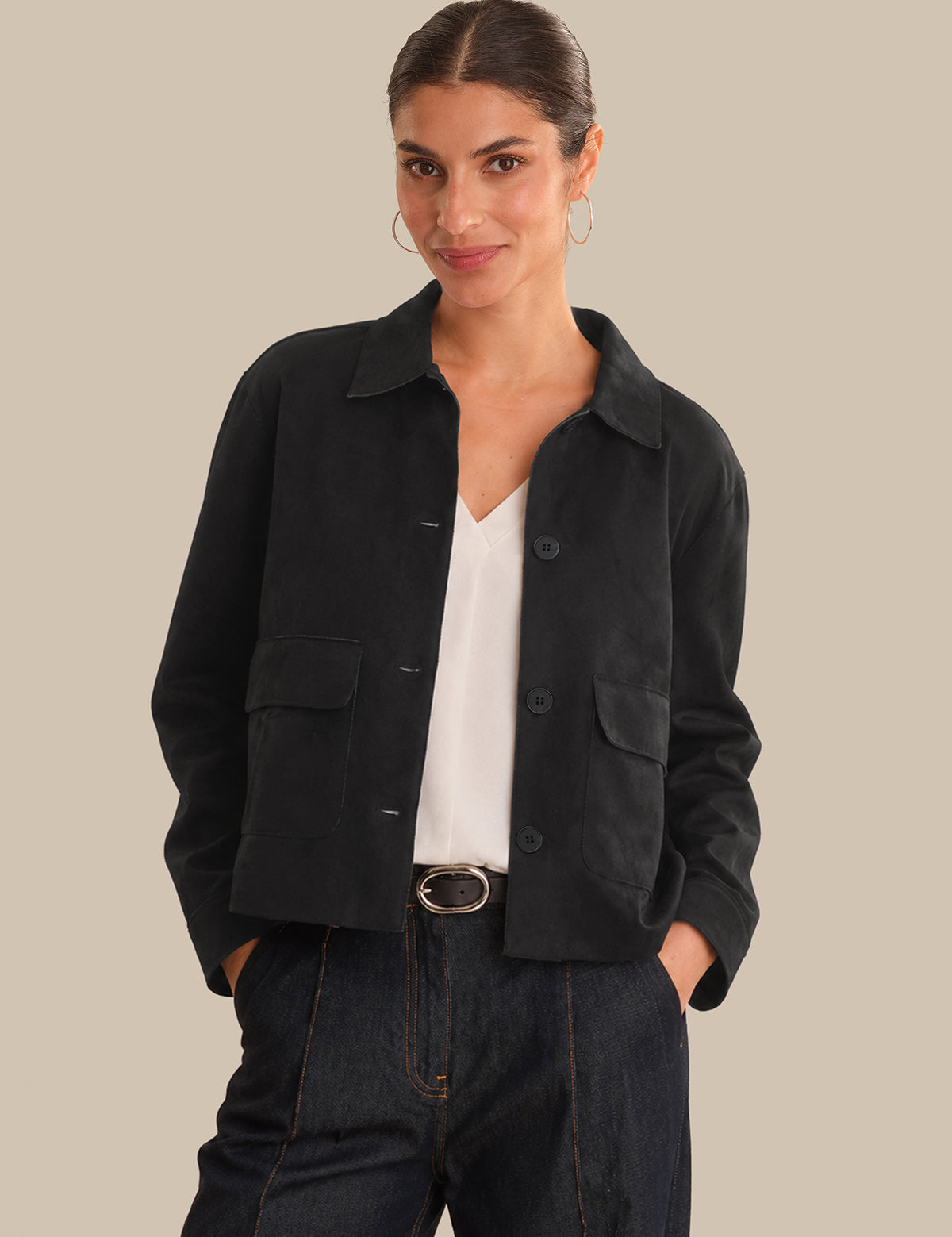 Woman wearing a black jacket over a white shirt on a beige background