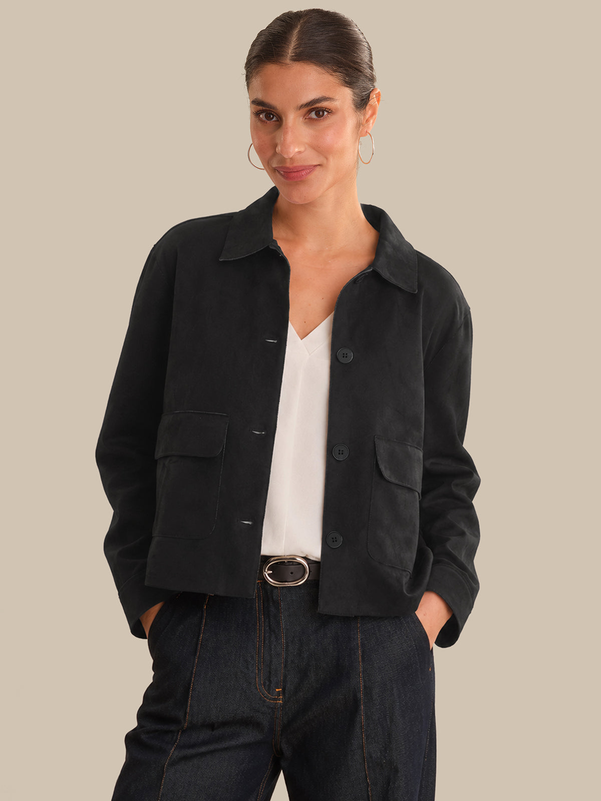 Woman wearing a black jacket over a white shirt on a beige background