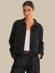 Woman wearing a black jacket over a white shirt on a beige background