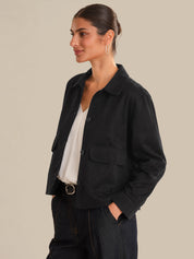 Woman wearing a black jacket over a white shirt on a beige background