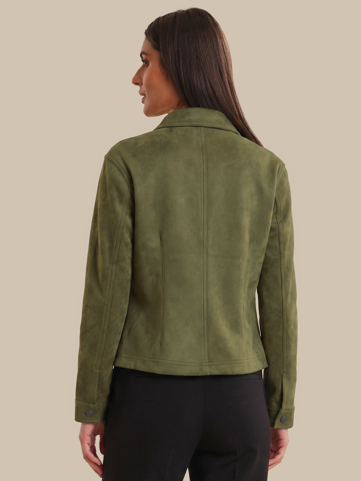 Woman wearing a green jacket on a beige background