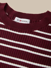 Close-up of a ribbed knit crewneck sweater with horizontal burgundy and white stripes, featuring a white neck label that reads '89th & MADISON'.