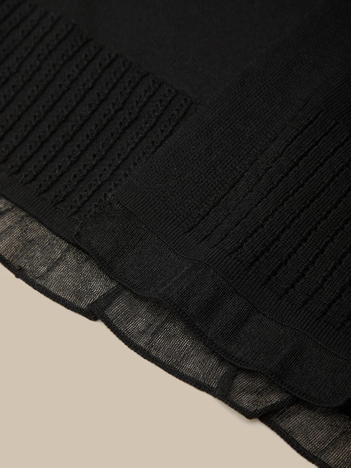Close-up of a black textured fabric with a beige background