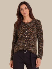 A woman modeling a long-sleeve leopard print knit top with a button-up front, paired with black pants, against a solid beige background.