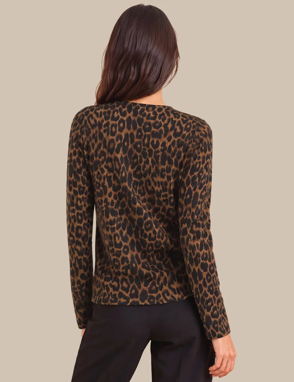 A woman shown from the back wearing a leopard-print long-sleeve top and black pants against a solid beige background.
