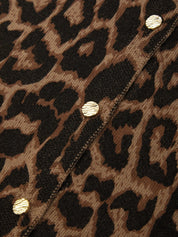 Close-up of a leopard print knit fabric with gold-tone round studs along a diagonal seam.