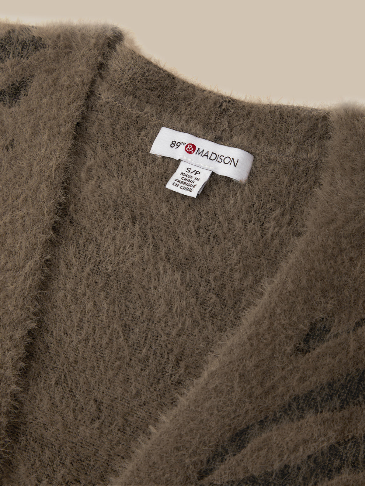 Close-up of a fuzzy brown knit garment with a white neck label reading 69 MADISON.