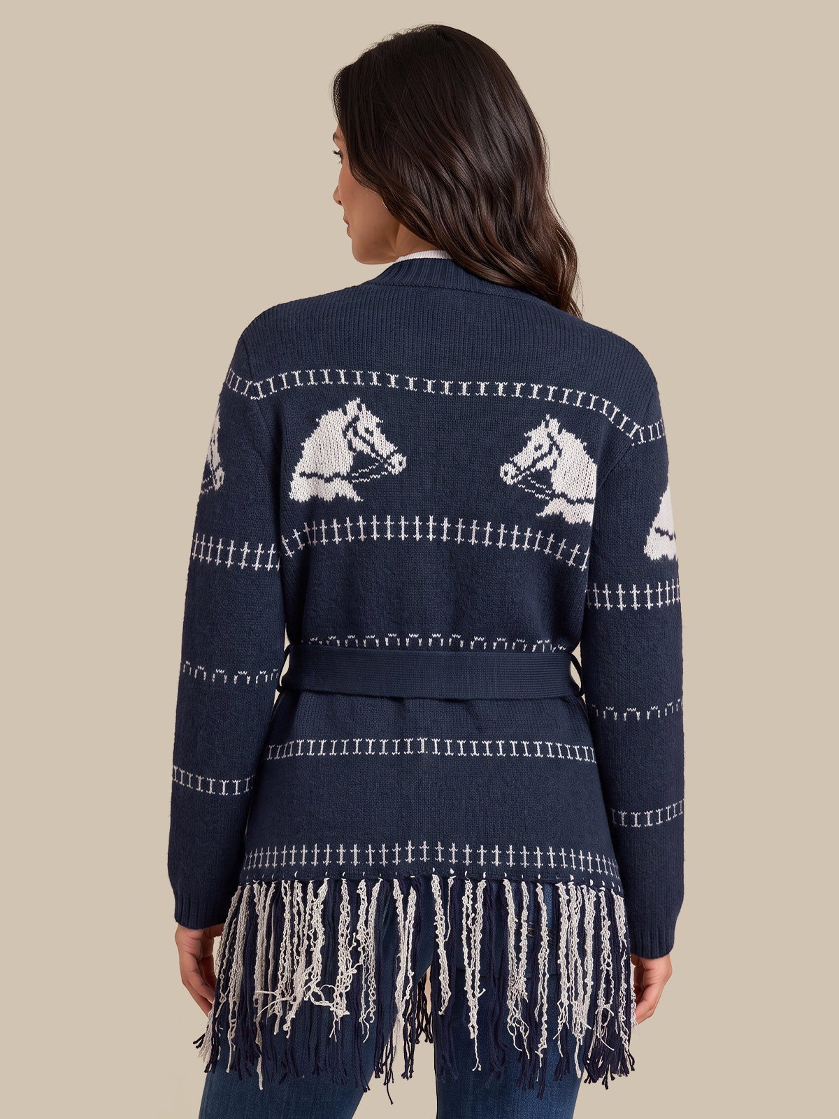 A woman shown from the back wearing a navy blue knit cardigan with white horse motifs and fringe trim, against a solid beige background.