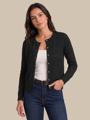 A woman modeling a black long-sleeve button-front cardigan over a white tank top and blue jeans, photographed against a plain beige studio background.