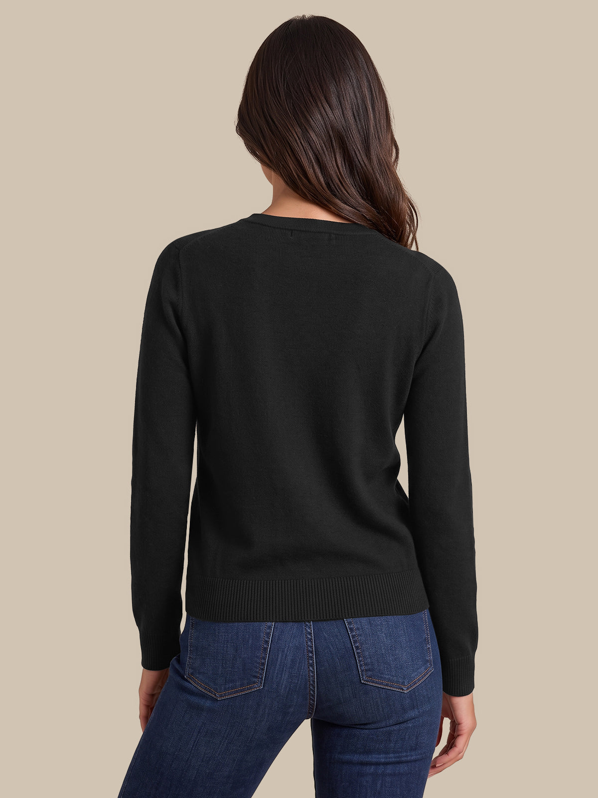 A woman shown from the back wearing a black long-sleeve knit sweater and blue jeans against a plain beige studio background.